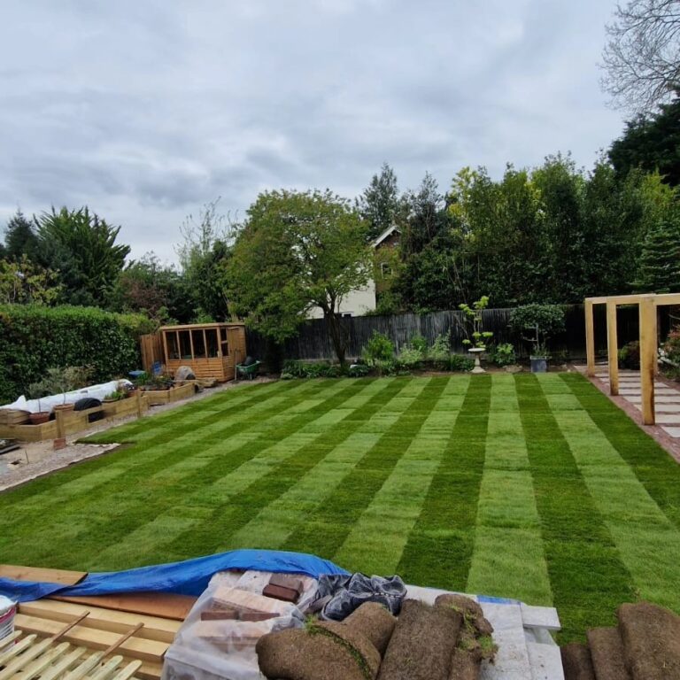 Freshly prepared garden soil ready for turf installation in Bearsted, with rolls of turf and tools visible.