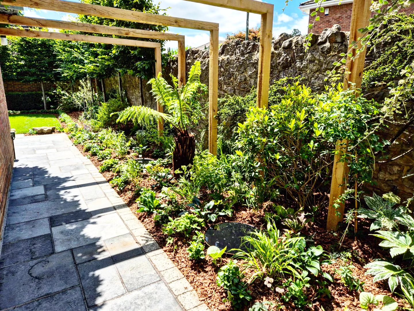 Layered garden walkway with wooden pergola and lush planting in Maidstone